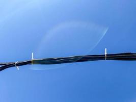 dickes schwarzes elektrisches industrielles Hochspannungsdrahtkabel auf blauem Himmelshintergrund foto