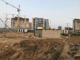 Schmutz auf einer Baustelle. Sandfurchen, Spuren von schweren Fahrzeugen. Es gibt Häuser in der Nähe, eine Kabine mit Transformatoren. Baulandschaft foto