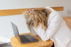 schöne Freiberuflerin, die sich müde und gestresst fühlt, während sie einen Laptop benutzt und von zu Hause aus arbeitet. Geschäftsfrau im Büro ist depressiv. foto