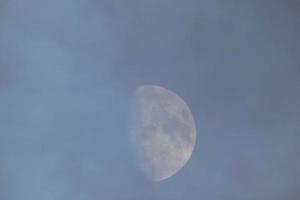 Fast-Vollmond, gesehen durch die Wolken bei Sonnenuntergang. foto