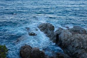 Meer, das die Felsen erreicht und Schaumspritzer erzeugt foto