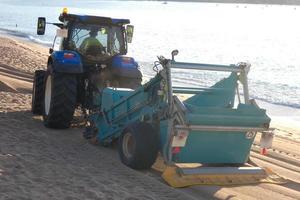 Traktor, der den weißen Sand am Strand reinigt foto
