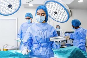 Chirurgin in chirurgischer Uniform, die chirurgische Instrumente im Operationssaal nimmt. junge Ärztin im Operationssaal des Krankenhauses foto