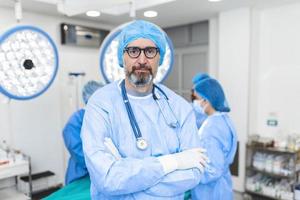 Porträt eines männlichen Chirurgen im Operationssaal, der in die Kamera blickt. arzt in schrubben und medizinischer maske im modernen krankenhaus-operationssaal. foto