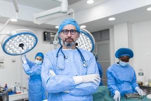 Porträt eines männlichen Chirurgen im Operationssaal, der in die Kamera blickt. Arzt in Peelings und medizinischer Maske im modernen Krankenhaus-Operationssaal. foto