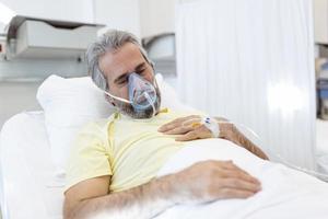 porträt eines pensionierten älteren mannes, der während des ausbruchs des coronavirus covid-19 langsam mit sauerstoffmaske atmet. alter kranker mann, der im krankenhausbett liegt und eine tödliche infektion behandelt foto