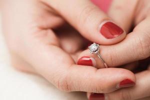 Nahaufnahme eines eleganten Verlobungsdiamantrings am Finger der Frau mit rosafarbenem Pullover im Winterkleid. foto