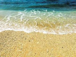 schöner sandstrand und sanfte blaue ozeanwelle foto