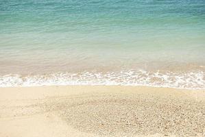 schöner sandstrand und sanfte blaue ozeanwelle foto