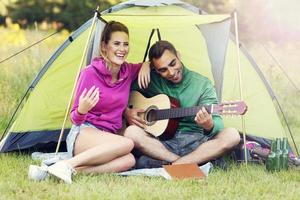 Paar Camping im Wald und Gitarre spielen foto