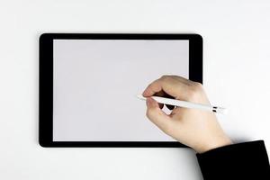 Blick von oben auf die Hand, die einen Stift hält und einen Tablet-Computer mit leerem weißen Bildschirm schreibt. mit Copy- und Business-Design foto