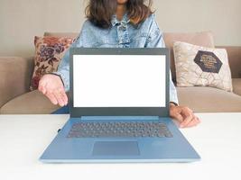 Modell-Laptop. asiatische frau, die neues modell laptop zeigt, um kaufberatung in lässiger jeansjacke auf weißem tisch zu empfehlen foto