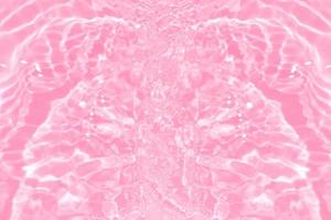 defocus verschwommene, transparente, rosafarbene, klare, ruhige Wasseroberflächenstruktur mit Spritzern und Blasen. trendiger abstrakter naturhintergrund. wasserwellen im sonnenlicht mit kopierraum. rosa aquarell glänzend foto