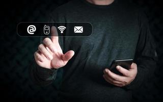 geschäftsmann verwendet smartphone und berührt auf dem virtuellen bildschirm kontaktsymbole, adresse, telefon, wifi, e-mail, kontaktieren sie uns und die mitarbeiter der kundensupport-hotline verbinden sich. foto