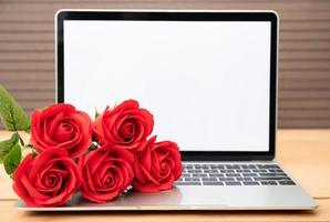 rote rose und laptop-modell auf holz foto