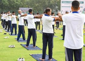neu-delhi, indien, 21. juni 2022 - gruppen-yoga-übungssitzung für menschen im yamuna-sportkomplex in delhi am internationalen yoga-tag, große gruppe von erwachsenen, die an yoga-kursen im cricket-stadion teilnehmen