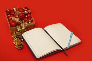 Öffnen Sie ein leeres Notizbuch neben einer Kiste mit Neujahrsspielzeug, das Konzept neuer Ziele im neuen Jahr foto