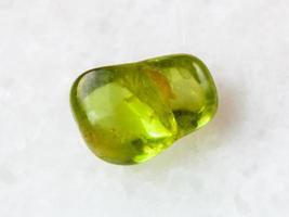 getrommelter Peridot-Edelstein auf Weiß foto