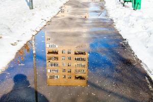 Reflexion des Hauses in Pfütze auf Fußweg foto