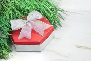 rote geschenkbox mit silberner schleife mit fichtenzweigen auf weißem tisch. Weihnachten, Neujahr, Geburtstag. Platz kopieren foto