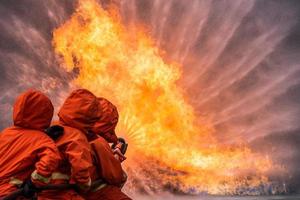 Feuerwehrrettungstraining zum Stoppen der brennenden Flamme, Feuerwehrmann trägt einen Schutzhelm und einen einheitlichen Sicherheitsanzug zum Schutz vor Verbrennungen mit einem Schlauch mit chemischem Wasserschaumspray. foto