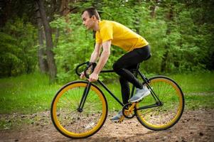 Porträt eines jungen Mannes, der sich auf einem Fahrrad fortbewegt. foto