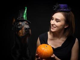Porträt eines Dobermann-Hundes mit einem Mädchenbesitzer. in Faschingskostümen mit Kürbis. foto