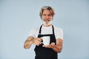 kellner mit getränken in den händen. älterer stilvoller moderner mann mit grauem haar und bart zuhause foto