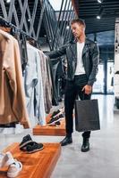 Wochenend-Shopping. junger mann im modernen geschäft mit neuen kleidern. elegante teure kleidung für männer foto