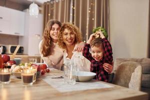 zu Abend essen. Die glückliche Familie von Mutter, Tochter und Sohn steht abends in der Küche foto