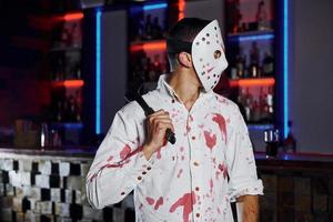 Porträt eines Mannes in Hockeymaske, der auf der thematischen Halloween-Party in gruseligem Make-up und Kostüm ist foto