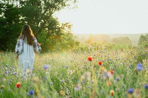 frau geht in der szenischen fotografie der kornblumenwiese spazieren foto