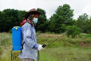 asiatischer landwirt verwendet herbizide, insektizide chemische sprays, um unkraut und insekten oder pflanzenkrankheiten auf landwirtschaftlichen flächen loszuwerden. Luftverschmutzung verursachen. umwelt-, landwirtschaftschemikalienkonzept. foto