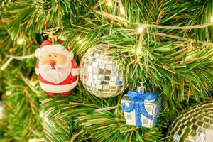 weihnachtsmann, kristallkugeln mit einer geschenkbox und weihnachtslichter, die am weihnachtstag auf kiefern dekoriert sind. foto