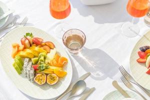 fröhlicher morgen elegante tischplatte im freien sonnige weiße umgebung mit frühstück obstteller, obstsalat. Bankett-Obstteller mit Sektgläsern foto