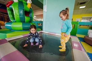 glückliche Schwestern, die auf dem Indoor-Spielplatz im Wassertrampolin spielen. foto