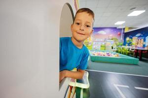 Junge spielt auf dem Spielplatz im Indoor-Spielzentrum und schaut vom Fenster aus. foto