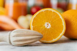 Nahaufnahme von geschnittener frischer Orange und Holzpresse. saftige Zitrusfrüchte auf verschwommenem Hintergrund. selektiver Fokus. Konzept für gesunde Ernährung foto