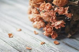getrocknete Rosen auf Holztisch, nostalgisches Vintage-Stillleben in sanften Beigetönen foto