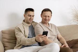 glückliches schwules paar mit lässiger kleidung, das smartphone hält und online mit freunden spricht, videoanruf hat. Homosexuelle Beziehungen und alternative Liebe. foto