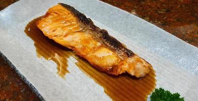 Gegrillter frischer Lachs mit Teriyaki-Sauce auf weißem Teller oder Gericht im japanischen Restaurant. draufsicht auf asiatisches oder fischfutter. nahaufnahme gegrillte meeresfrüchte.