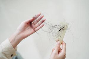 asiatische Frau hat Probleme mit langem Haarausfall an der Kammbürste. foto