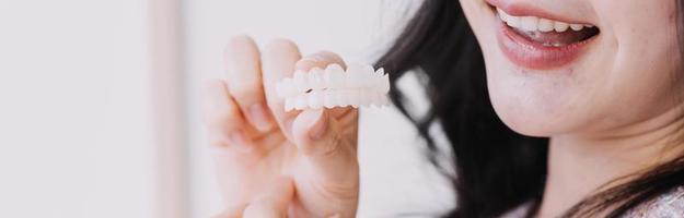 Stomatologie-Konzept, Teilporträt eines Mädchens mit starken weißen Zähnen, das in die Kamera schaut und lächelt, Finger in der Nähe des Gesichts. Nahaufnahme der jungen Frau beim Zahnarzt, Studio, drinnen foto