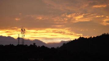 die schöne Aussicht auf den Sonnenuntergang mit den bunten Wolken und der Bergsilhouette als Hintergrund foto