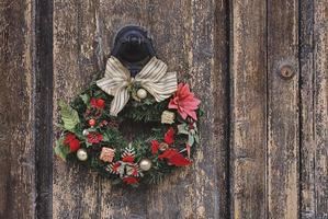 weihnachtskronenkranz auf einer alten holztür. traditionelle wohnkultur während der weihnachtszeit foto