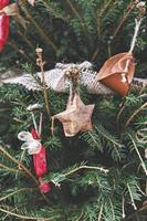 Vintage Holzstern und Lederspielzeug am Weihnachtsbaum. Natürliche DIY-Ornamente für den Weihnachtsbaum, Null-Abfall-Weihnachten foto