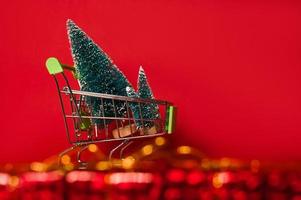 Gruppe von künstlichem Tannenbaum in einem Wagen. Exemplar. Feiertagsverkäufe und Rabatte. Banner mit Bokeh. foto