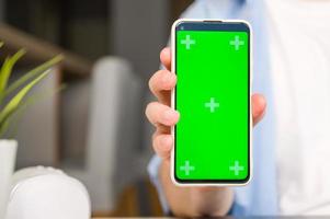 Modellbild eines Mannes, der ein Smartphone mit grünem Chroma-Bildschirm hält und zeigt foto
