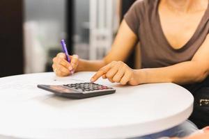 Geschäftsfrau hält Stift in der Hand, der am Taschenrechner arbeitet, um Geschäftsdaten zu berechnen. foto