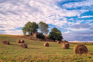 Malerischer Blick auf Heuballen auf dem Feld in der Provence Südfrankreich gegen Bäume und blauer Himmel und weiße Wolken foto